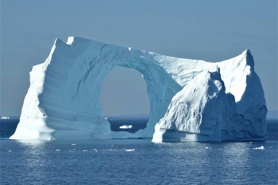 Naturally sculpted iceberg with a large arch formation floating in calm polar waters