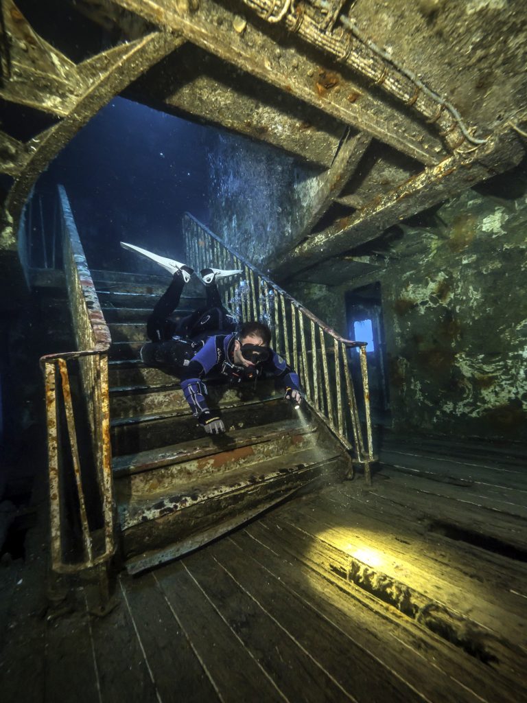 Diver navigating interior staircase of the Karwela shipwreck in Gozo, Malta during Polar Prep® Series wreck training.