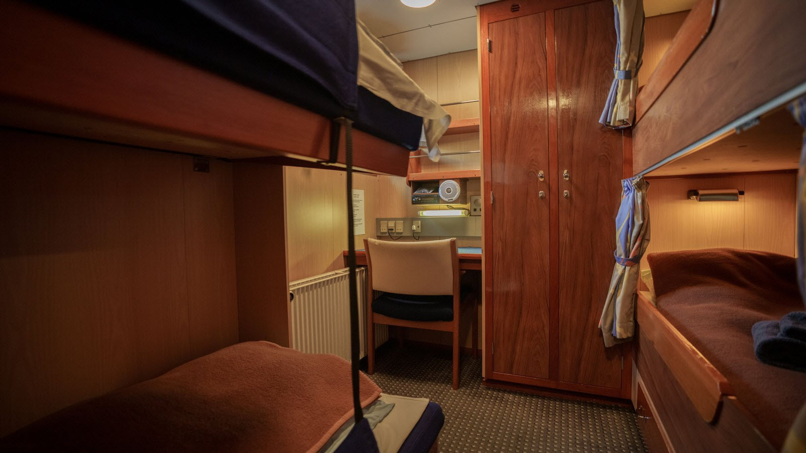 A four-berth quad cabin aboard M/V Sisak with bunks, a desk, and wardrobe
