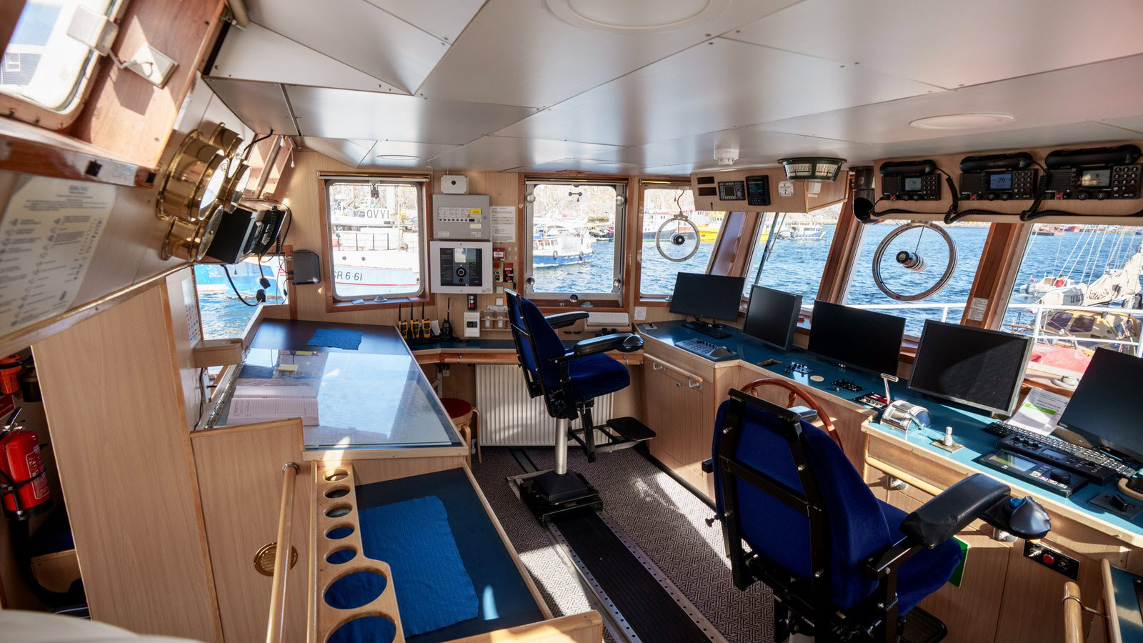 The wheelhouse aboard M/V Sisak with helm chairs, console monitors, and harbor views