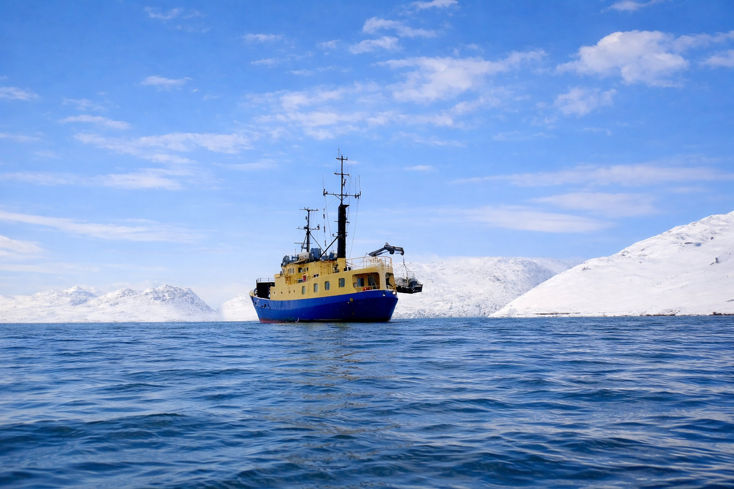 M/S Tulu at anchor in calm Arctic waters below snow-covered Greenland mountains