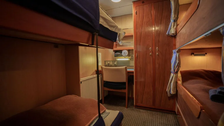 A four-berth quad cabin aboard M/V Sisak with bunks, a desk, and wardrobe